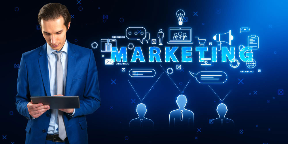 Businessman in blue suit using a tablet on the left; glowing neon "MARKETING" text and connected marketing icons and user silhouettes on a dark blue background.